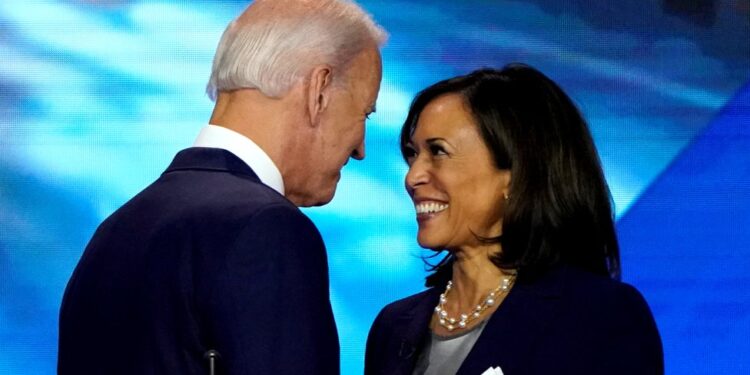 Joe Biden e Kamala Harris sorridono l'uno all'altra durante un evento pubblico.