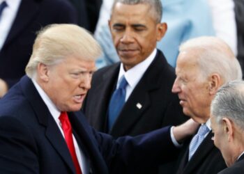 Donald Trump parla con Joe Biden, mentre Barack Obama osserva in secondo piano durante un evento ufficiale.
