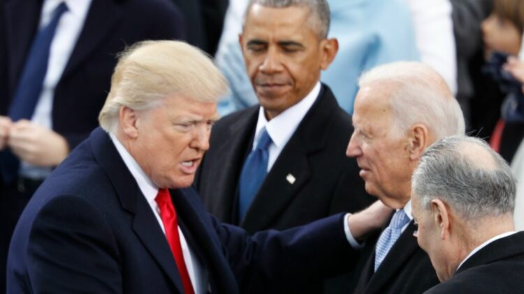 Donald Trump parla con Joe Biden, mentre Barack Obama osserva in secondo piano durante un evento ufficiale.